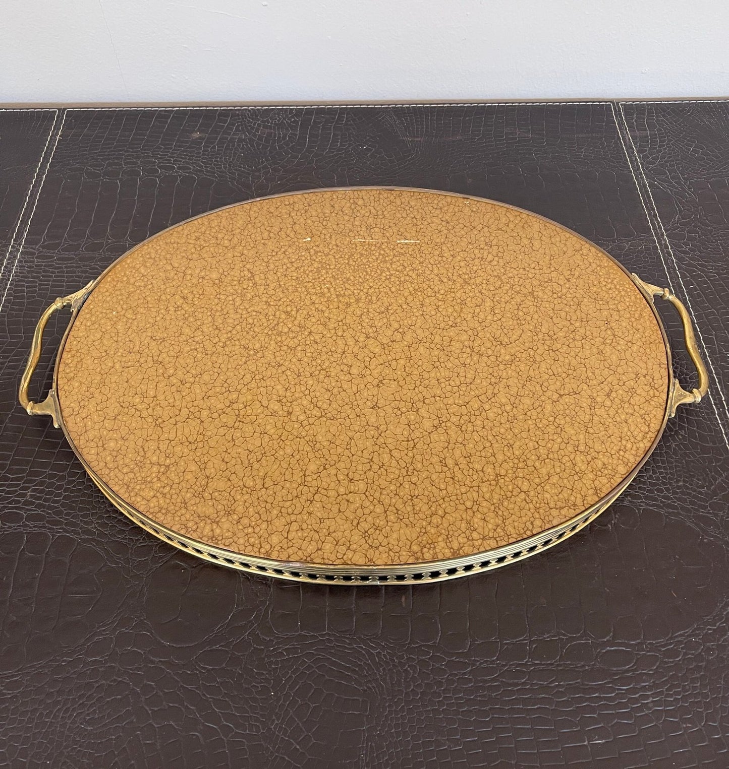 Vassoio ovale in metallo dorato è un pezzo unico che cattura l’essenza della tradizione e del fascino vintage.