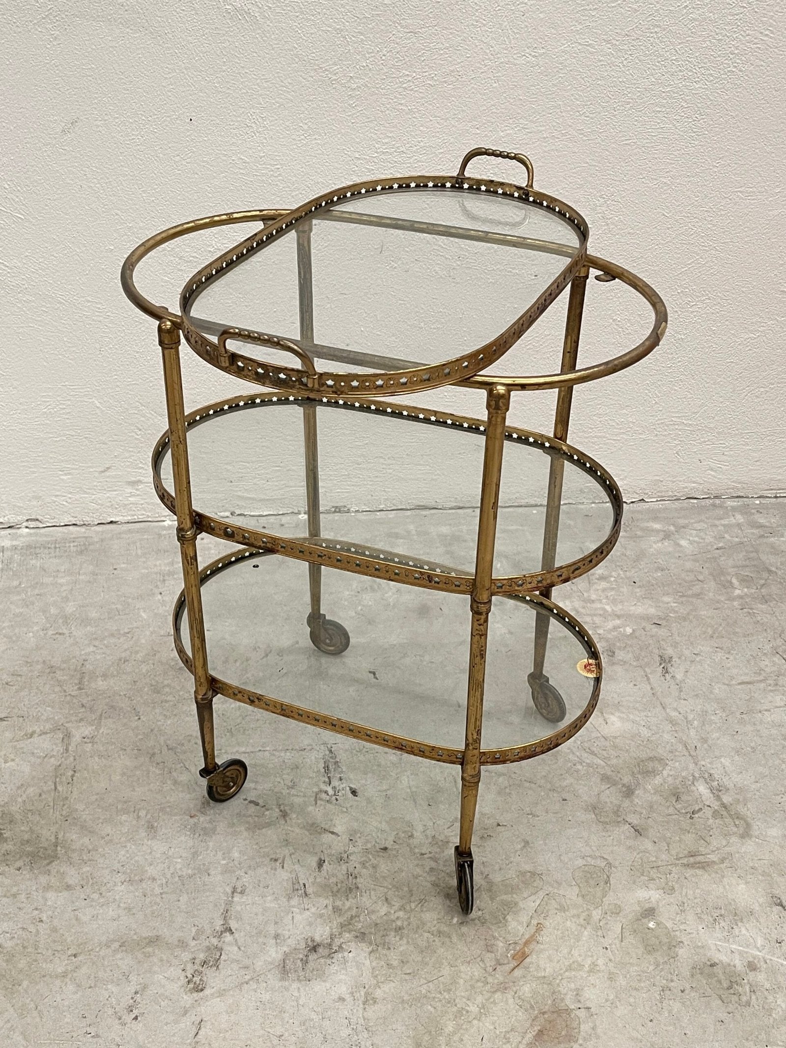 Carrello da bar vintage a tre ripiani, in stile hollywood regency, con struttura in ottone dorato e ripiani in vetro trasparente.