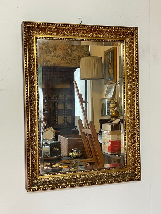 Specchiera vintage con cornice in legno finemente intagliata e dorata, decorata con eleganti motivi floreali in rilievo.