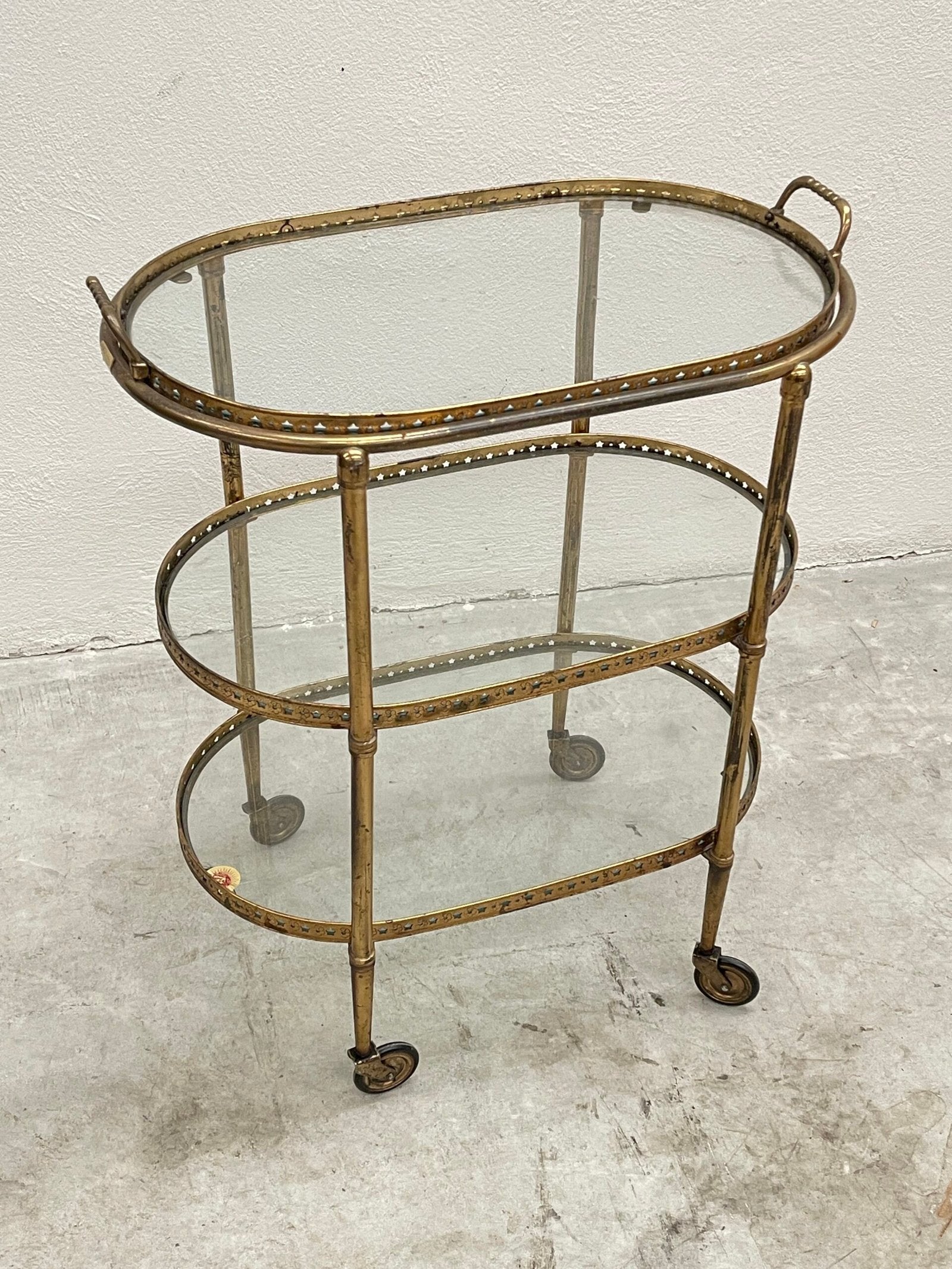 Carrello da bar vintage a tre ripiani, in stile hollywood regency, con struttura in ottone dorato e ripiani in vetro trasparente.