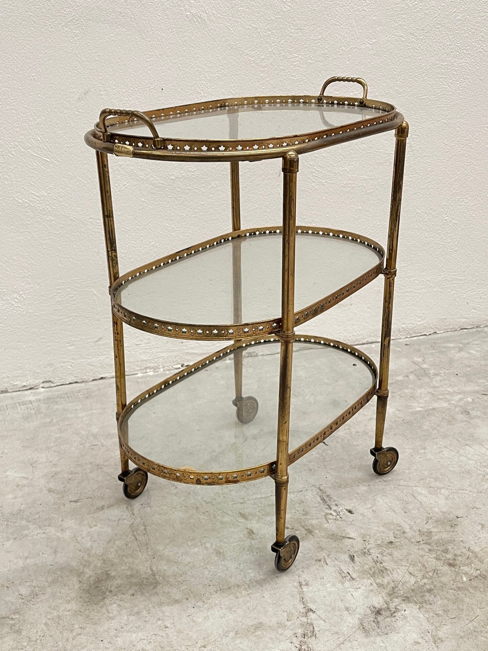 Carrello da bar vintage a tre ripiani, in stile hollywood regency, con struttura in ottone dorato e ripiani in vetro trasparente.